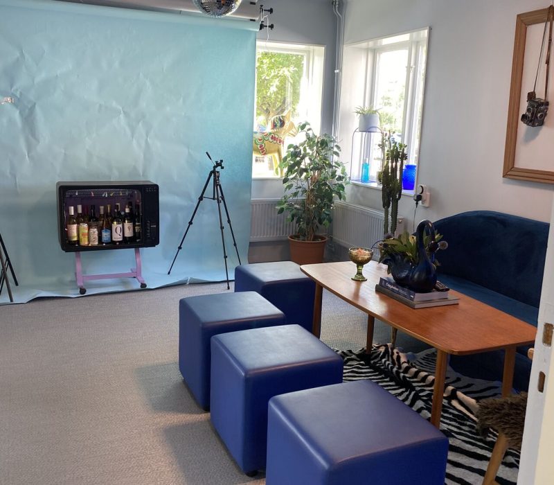 Rum med blå sittpuffar, soffa och bord. I taket hänger en discokula